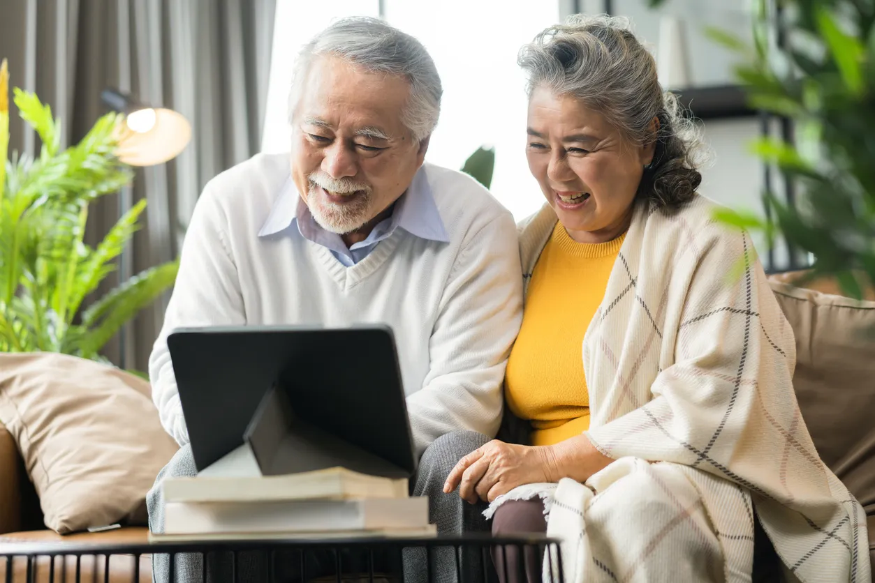 A couple looking at a tablet while sitting on a sofa