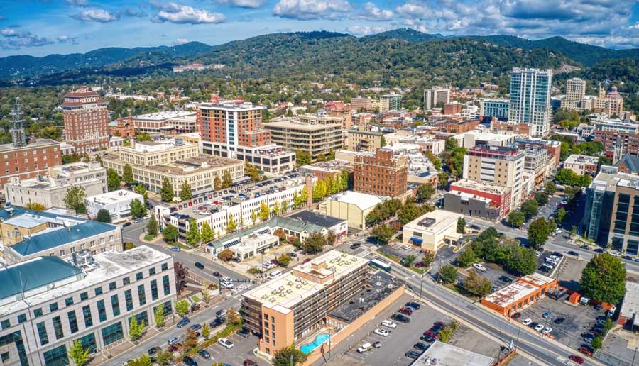Aerial view of downtown Asheville with the Blue Ridge Mountains behind it