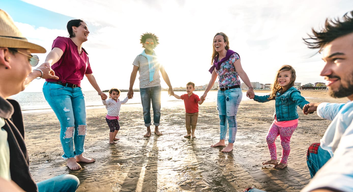 Young families holding hands and dancing in a circle on the beach