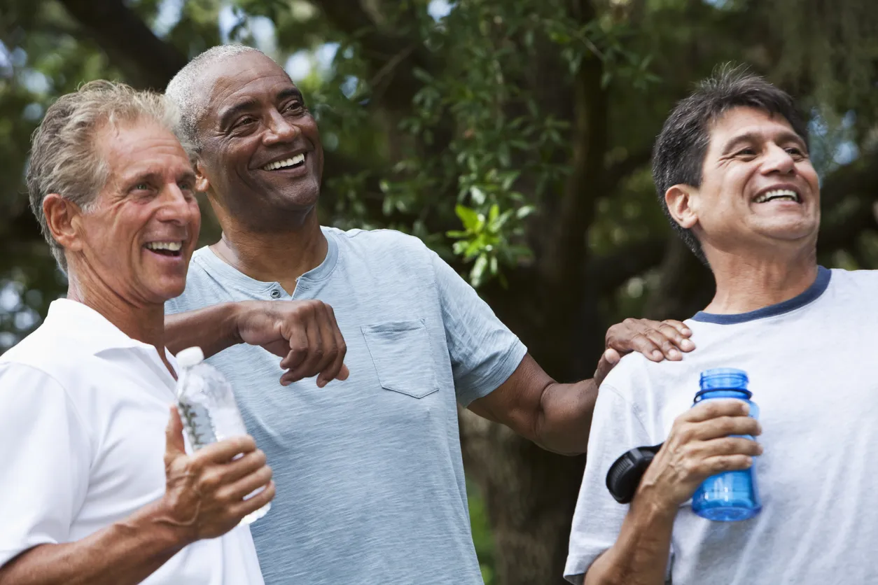 Three older men laughing together outdoors