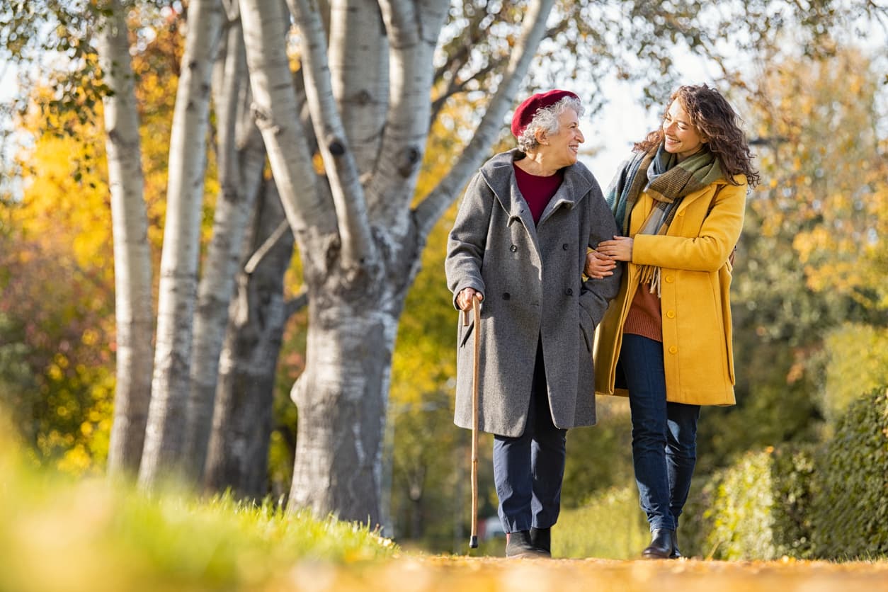 Young woman walking with her grandmother in an autumn park