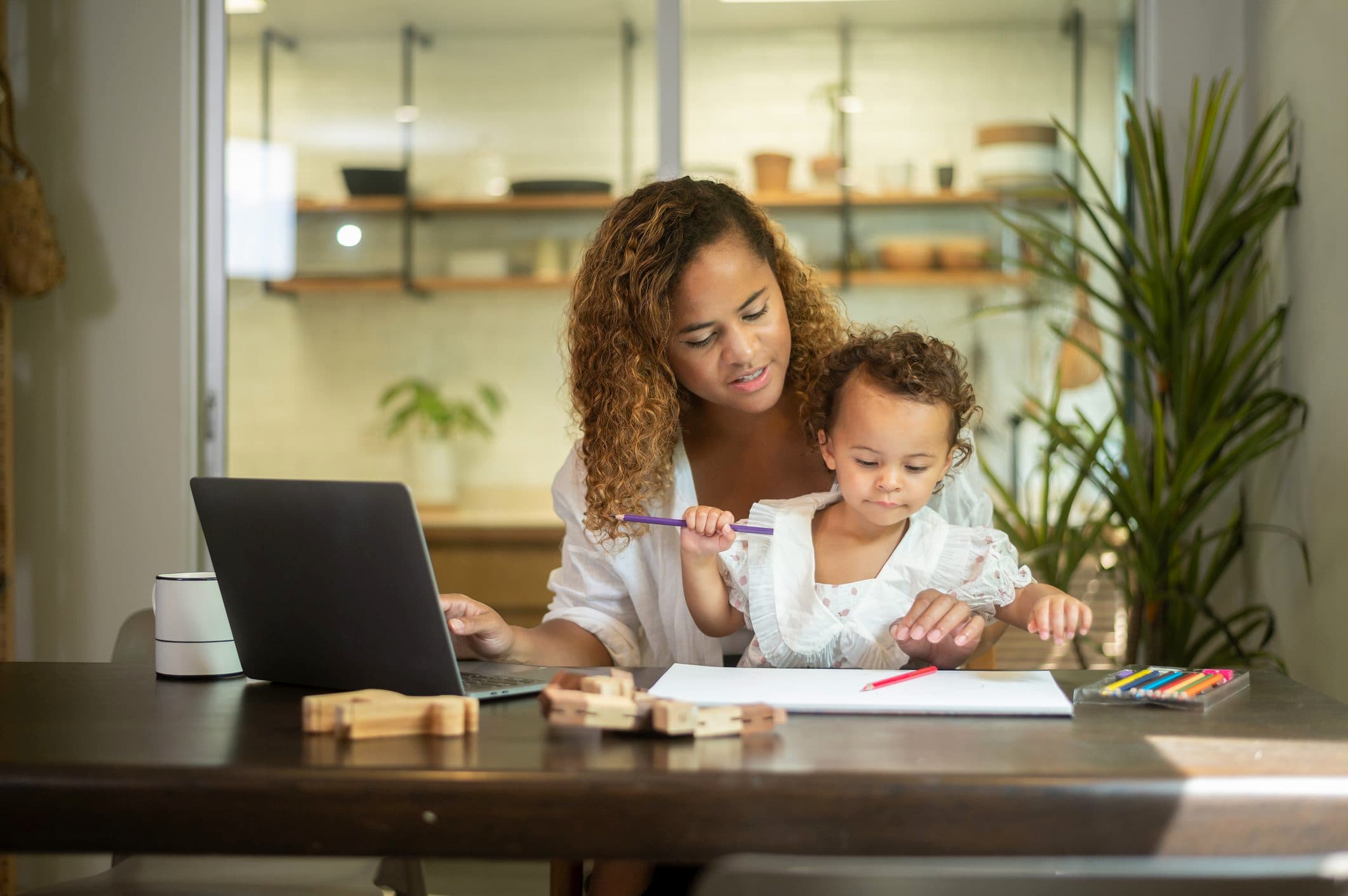 Mother working on a laptop with her toddler on her lap