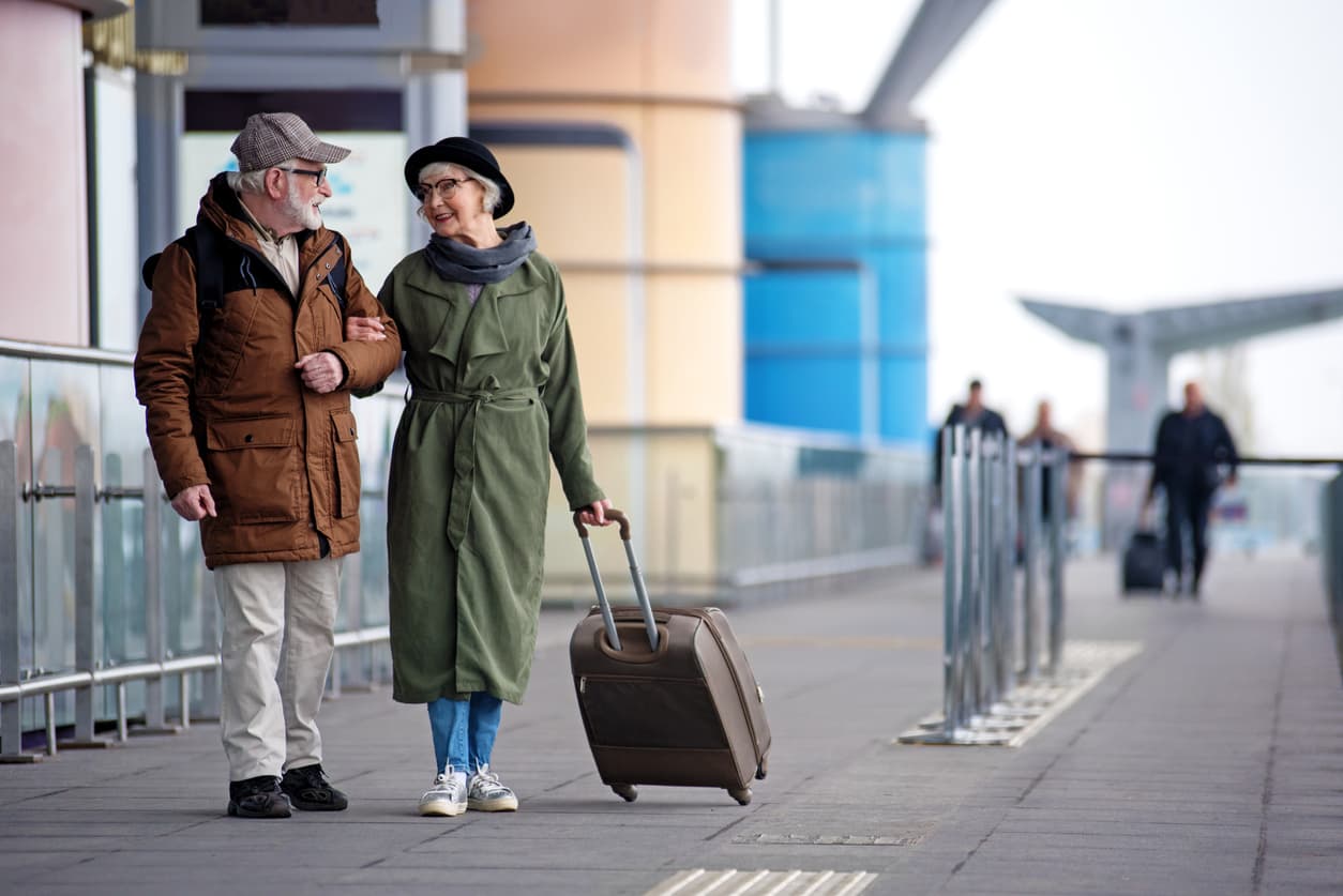 Retired couple with a suitcase talking on a walkway